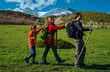 Family of three hikers walk holding on to each other in the mountains in spring