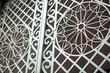 Close-up of intricate white ironwork on a gate during daytime