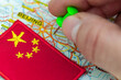 Travel to China. A hand inserting a pin marking the direction of the trip, an embroidered Chinese flag. Vacation or business travel concept