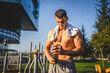 © Miljan Živković - One caucasian man young male athlete take a brake during outdoor training in the park outdoor gym hold supplement shaker in hand happy confident strong copy space