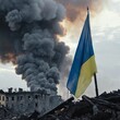 Ukraine flag flying proudly in the wind, smoke and destruction - aftermath of war