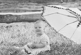 Fototapeta  - beautiful baby in a polka-dot dress is sitting nea umbrella umbrella