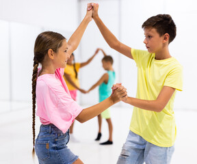 Wall Mural - Kids in pairs exercising salsa moves together during group dance class.