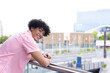 In modern office, biracial young man leaning on railing, smiling at camera, copy space