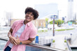 In modern office, biracial young man leaning on railing, smiling, copy space
