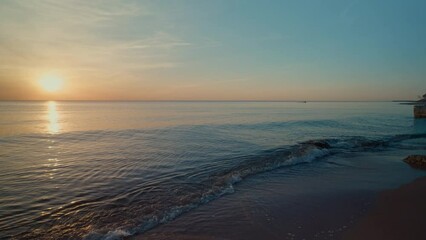 Poster - The ocean is calm and the sun is setting, creating a serene and peaceful atmosphere. The water is a deep blue color, and the sky is a mix of orange and purple hues. The scene is perfect for relaxation