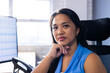 © Wavebreak Media - At office, biracial businesswoman wearing blue top, sitting, looking at camera