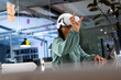 © Wavebreak Media - Working late at office, biracial businesswoman wearing VR headset, pointing upward