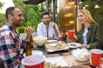 Cheerful friends having picnic outdoor drinking beer enjoying weekend