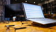 © Wavebreak Media - At office, laptop on wooden desk displaying sales tracker, working late