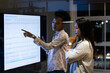 © Wavebreak Media - At office, diverse female colleagues reviewing sales tracker, working late