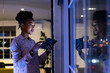 © Wavebreak Media - African American businesswoman with tablet looks out window, working late at office, copy space