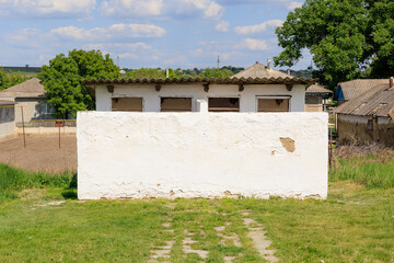 Wall Mural - Outdoor school toilet. White wall with few buildings in the background