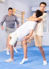 Wall Mural - Teens learn doing throw over shoulder in self-defense lesson in modern sport gym