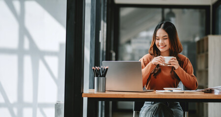 Wall Mural - Businesswoman takes pleasure in a coffee break at her desk, amidst a session of productive work.