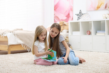 Sticker - Cute little sisters reading book together at home