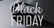 Image of black friday text over rolled up black paper on grey background