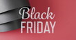 Image of black friday text over rolled up black paper on red background