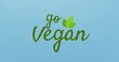 Image of green text reading go vegan with leaf design, resting on a blue background