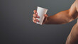© VISUAL BACKGROUND - A shirtless man holding a cup of coffee.
