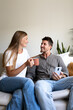 Vertical portrait of happy couple enjoying morning time together drinking coffee and relaxing sitting on the couch.