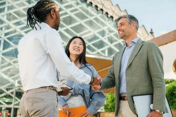 multiracial business people shaking hands outside