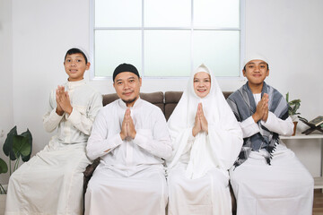 Asian muslim family in white outfit showing greeting hands gesture