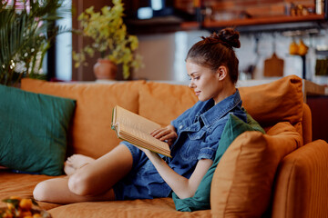 Relaxing evening at home Woman sitting on orange couch reading book and holding glass of wine