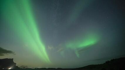 Wall Mural - Clouds fly in the dark night sky adorned with mesmerizing dance of the northern lights.
