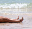 Legs of a girl lying on white sand by the sea