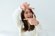 Young asian woman happy and making frame with fingers on white background in house