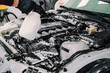 © Wirestock - Person wearing gloves cleaning the car engine and interior parts