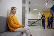 Smiling woman patient sitting at waiting area in hospital