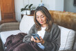 © Iryna - unhappy Asian mature woman sitting on sofa using phone Lifestyle concept