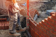 Bricklayer with masonry trowel working on curved wall building site