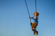 Joyful kid swinging on a swing. Happiness children. Child having fun on a swing outdoor. Craziness and freedom. Kid playing on swing-set outdoor. Playful child swinging very high to the sky.