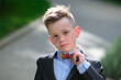 Fashion kid boy in suit and bow tie. Lifestyle portrait of cute kid outdoors. Summer kids outdoor portrait.