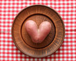 funny potato in the shape of a heart on a clay plate, top view, flat layout. an ugly root vegetable.