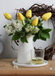 blooming lilacs and yellow tulips in a white jug on the table. floristry, making bouquets. spring composition with flowers.