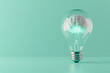 © xadartstudio - A 3D illustration of a crystal-clear light bulb with a luminous brain inside, placed on a pastel mint background for a fresh idea concept