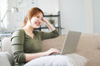 Happy casual beautiful woman working on a laptop sitting on the couch in the house.