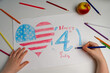 The American flag is drawn with pencils by children's hands. Children's hands draw a flag. Patriotism, independence day, flag day concept. Day of Remembrance