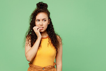 Wall Mural - Young sad disappointed dissatisfied woman of African American ethnicity wear yellow tank shirt top look aside on area isolated on plain pastel light green background studio portrait Lifestyle concept