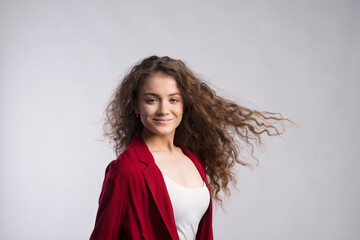 Sticker - Portrait of a gorgeous teenage girl with curly hair in red blazer. Studio shot, white background with copy space