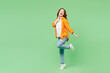 © ViDi Studio - Full body side profile view young ginger woman she wearing orange shirt white t-shirt casual clothes put hand on face raise up leg isolated on plain pastel light green background. Lifestyle concept.