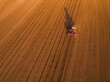 Aerial shot of a farmer seeding, sowing crops at field. Sowing is the process of planting seeds in the ground as part of the early spring time agricultural activities.