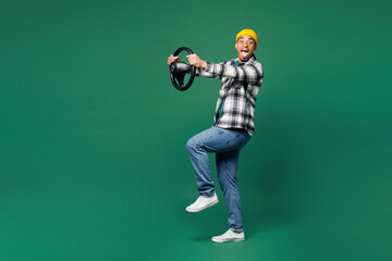 Full body side view young man of African American ethnicity wear shirt blue t-shirt yellow hat hold steering wheel driving car look aside isolated on plain green background studio. Lifestyle concept.