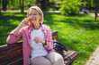 Portrait of happy mature woman in park. She is enjoying sunny day in park.