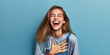 © ilolab - Young caucasian woman isolated on blue background laughs out loudly keeping hand on chest.