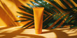 Vibrant orange sunscreen tube stands against a backdrop of lush green tropical leaves with dramatic shadows